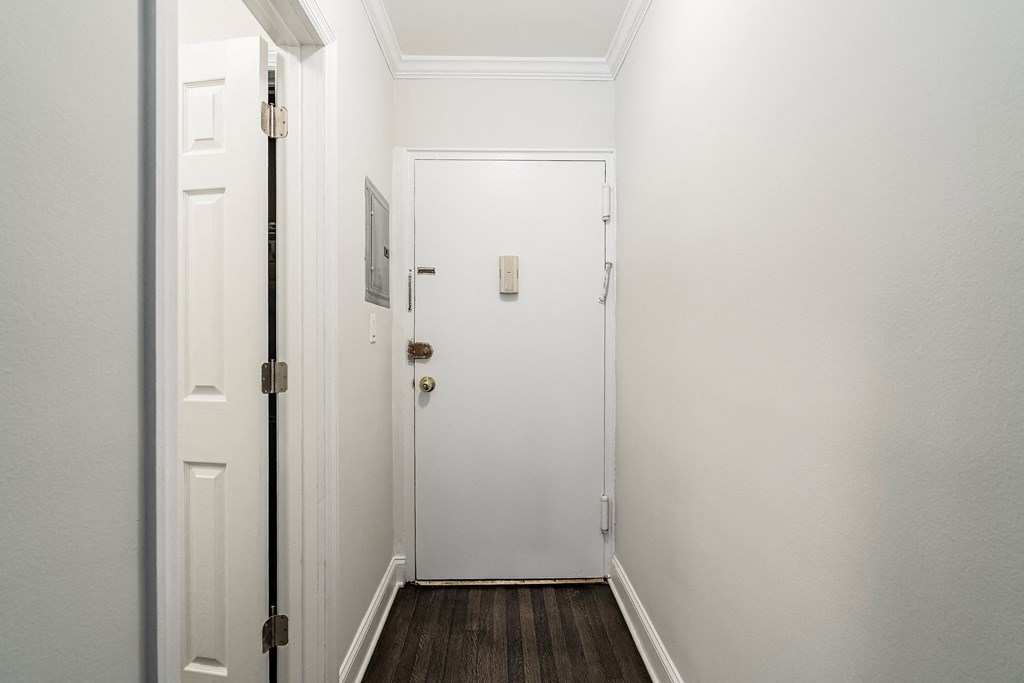 a hallway with white walls and a white door