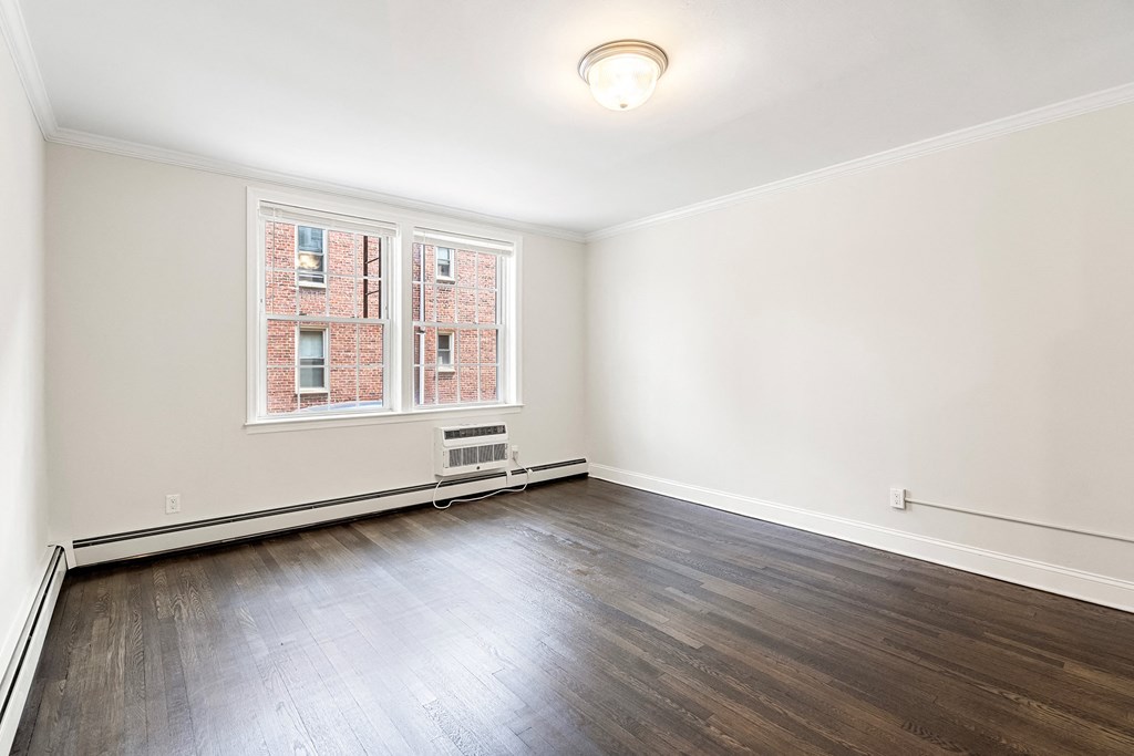 an empty living room with wood flooring and a window