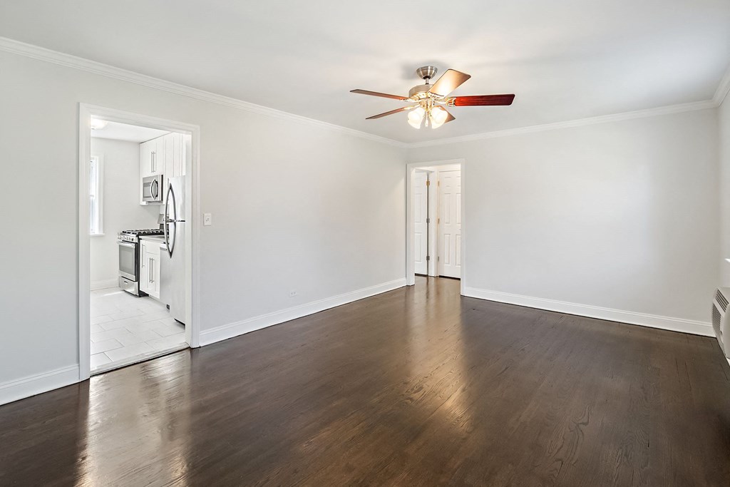 an empty living room with white walls and a ceiling fan