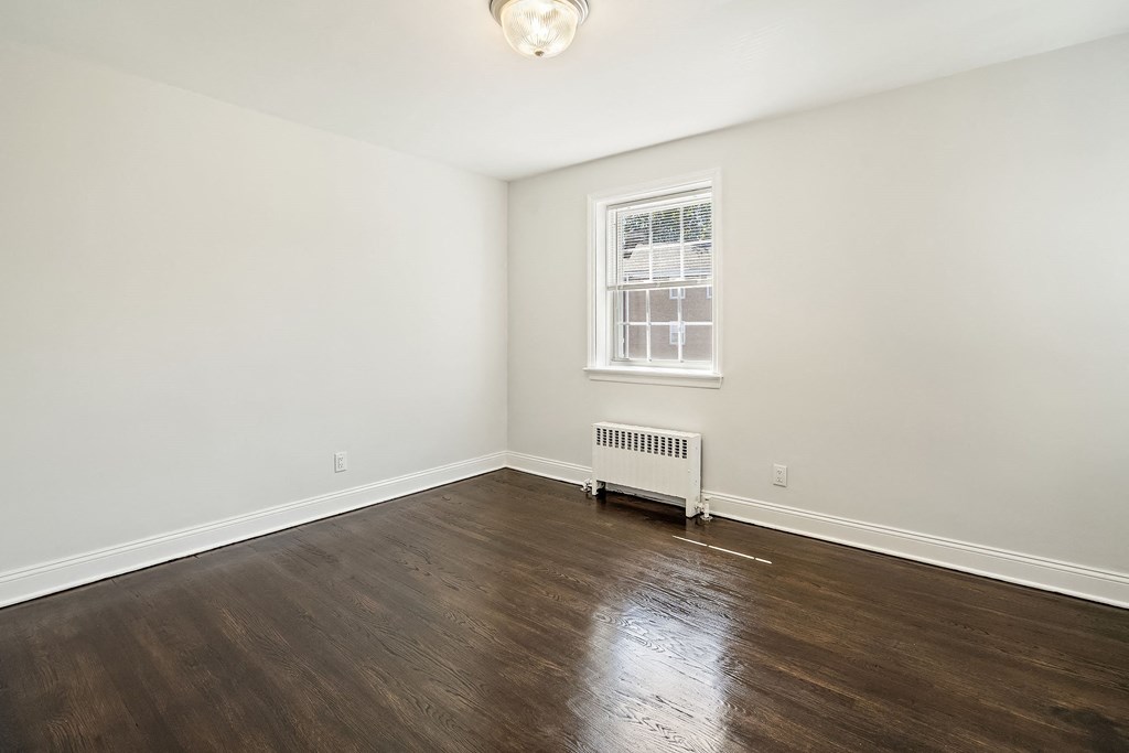 an empty living room with wood floors and a window