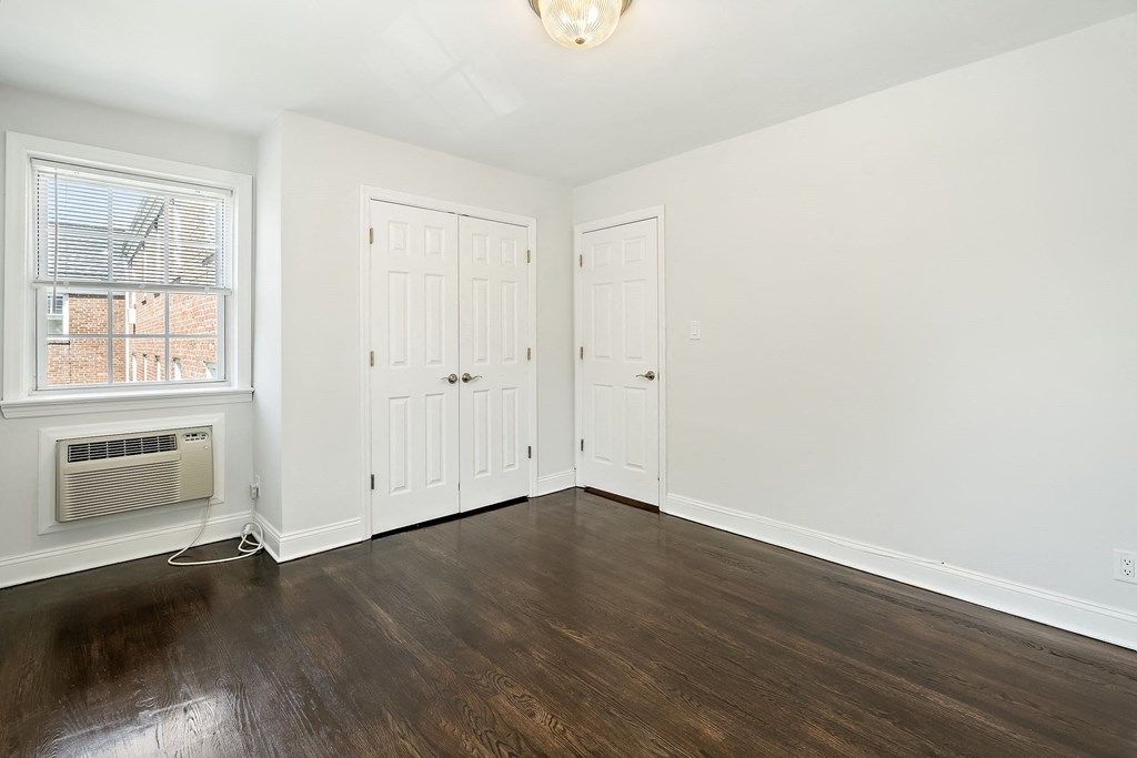 a living room with white walls and wood floors and a window