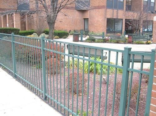 a green fence in front of a brick building