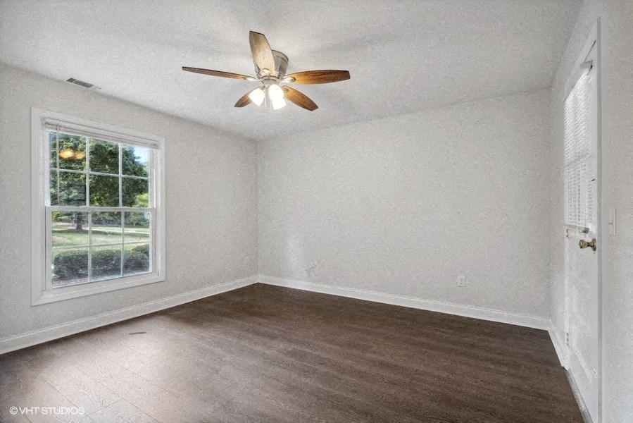an empty bedroom with a ceiling fan and a window