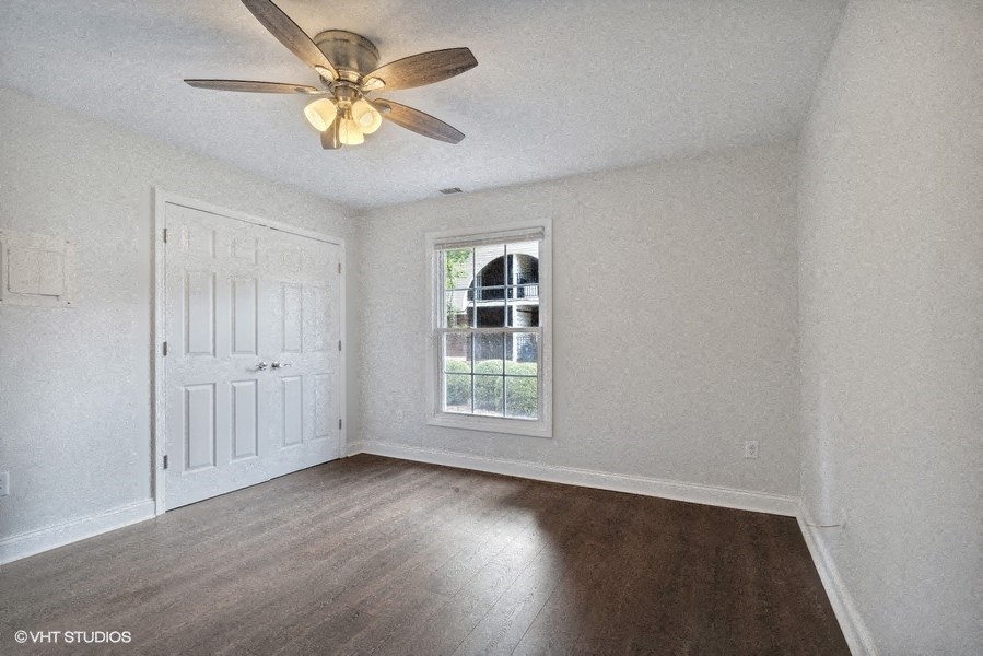 an empty living room with a ceiling fan and a window
