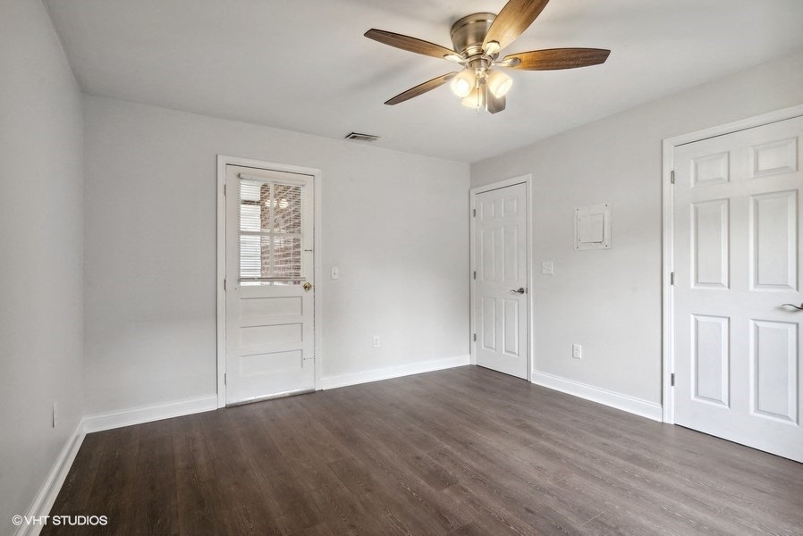 an empty living room with white walls and a ceiling fan
