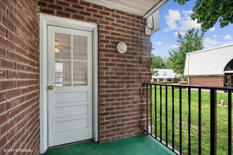 the entrance to a brick house with a white door and a balcony