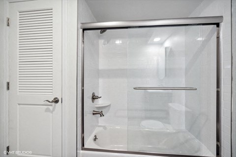 a white bathroom with a shower and a white door