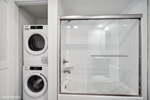a bathroom with a washing machine and a glass door