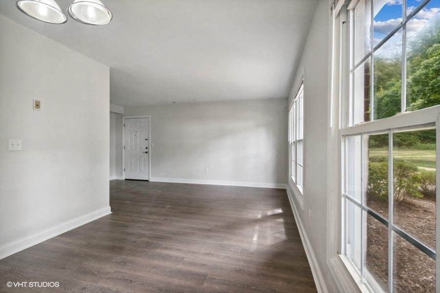an empty living room with large windows and white walls