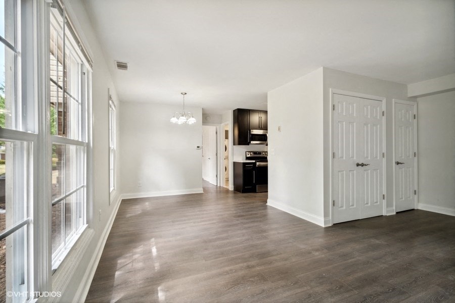 the living room and dining room of an empty home with white walls and wood floors