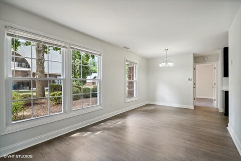 an empty living room with large windows and wood flooring