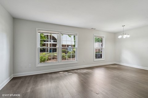 an empty living room with large windows and wood flooring