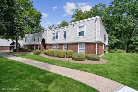 a white house with a walkway in front of a green yard