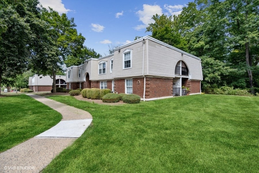 a white and brick house with a walkway in front of it