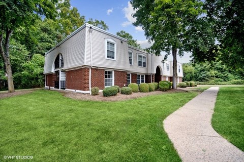 a white and brick house with a sidewalk in front of it
