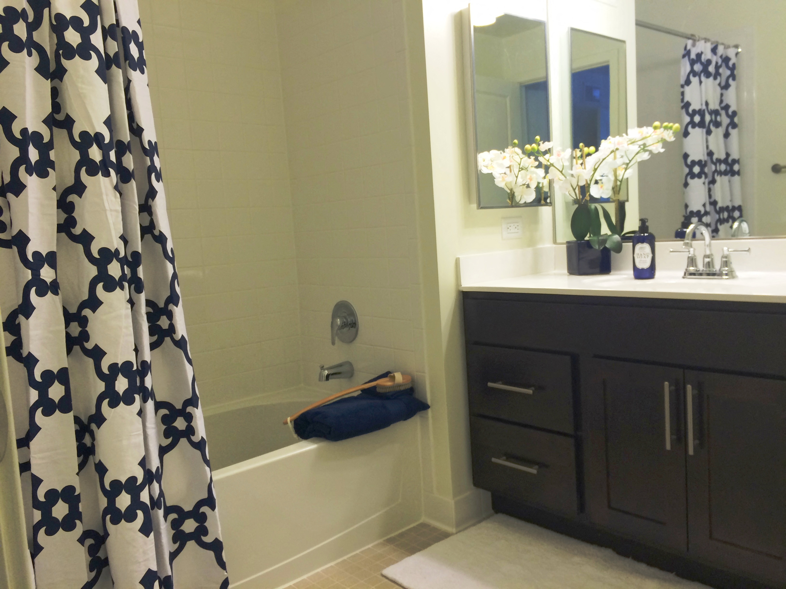 the bathroom has a shower and a sink and a blue and white shower curtain