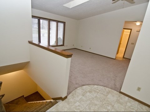 an empty living room with a staircase and a window