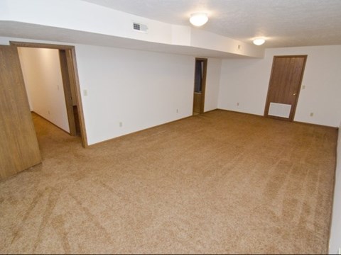 an empty living room with two doors and a carpeted floor