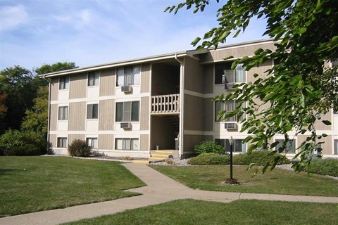 an apartment building with a sidewalk in the grass