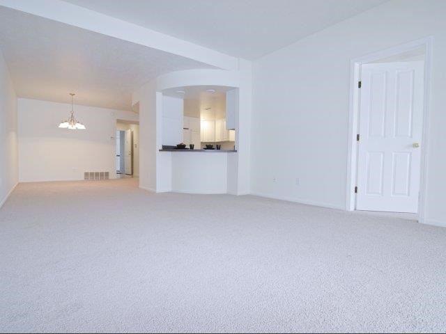 an empty living room with a door to the kitchen