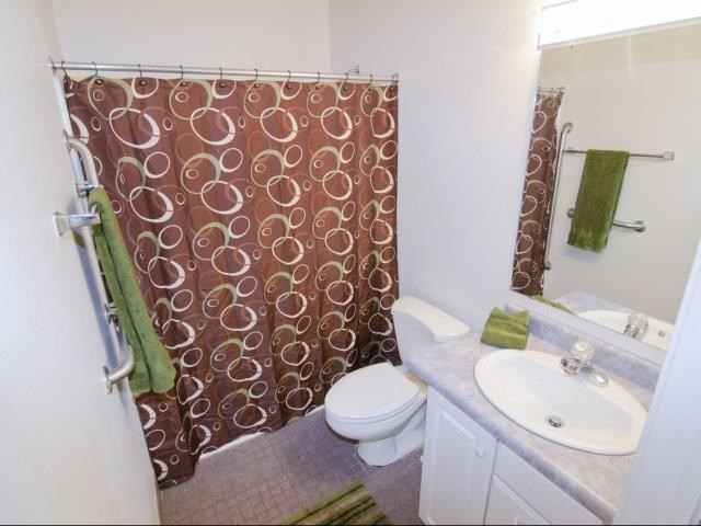 a bathroom with a brown shower curtain and a toilet and sink