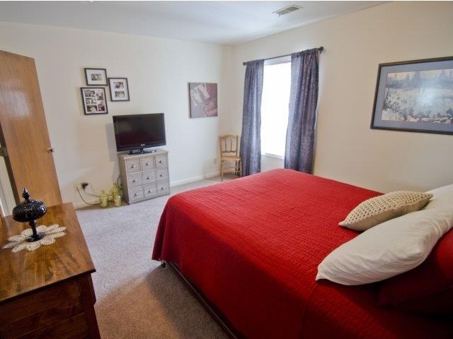 a bedroom with a red bed and a television