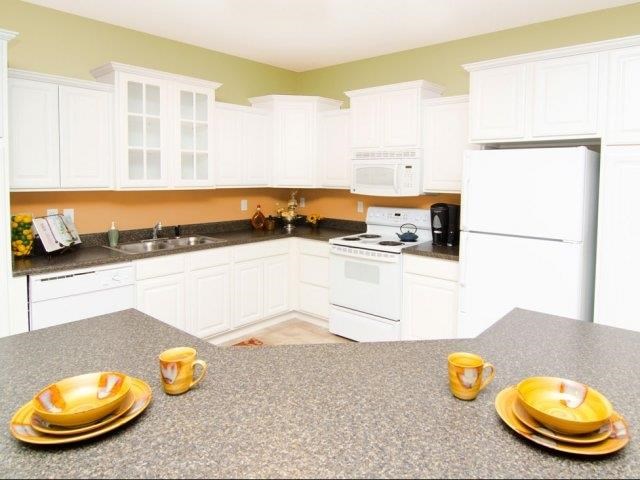 a kitchen with white cabinets and a table with plates and cups