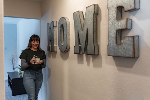 a woman standing next to a wall with some metal letters spelling out the word home
