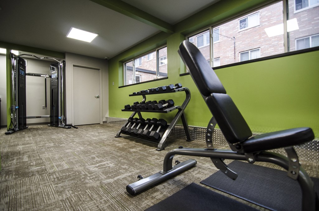 a gym with weights and a chair in the corner of a room