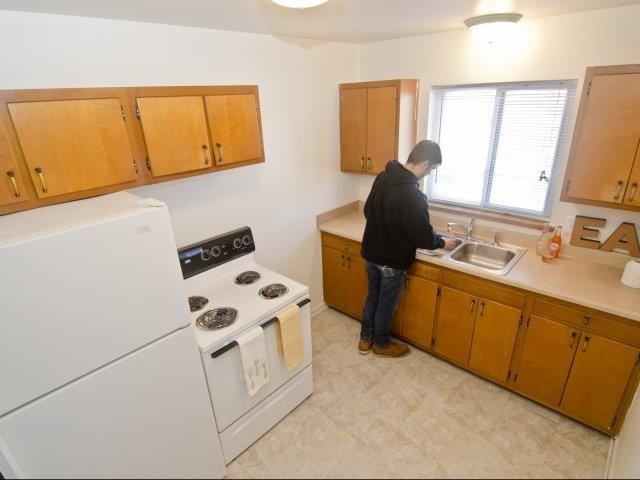 a man standing at a sink in a kitchen