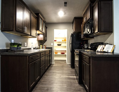 a kitchen with dark wood cabinets and a black refrigerator