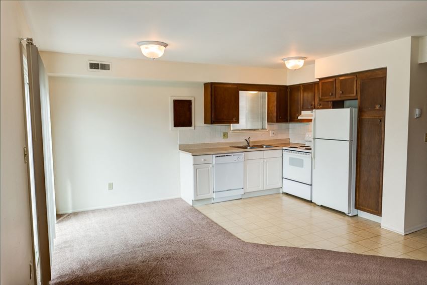 an empty kitchen with white appliances and wooden cabinets
