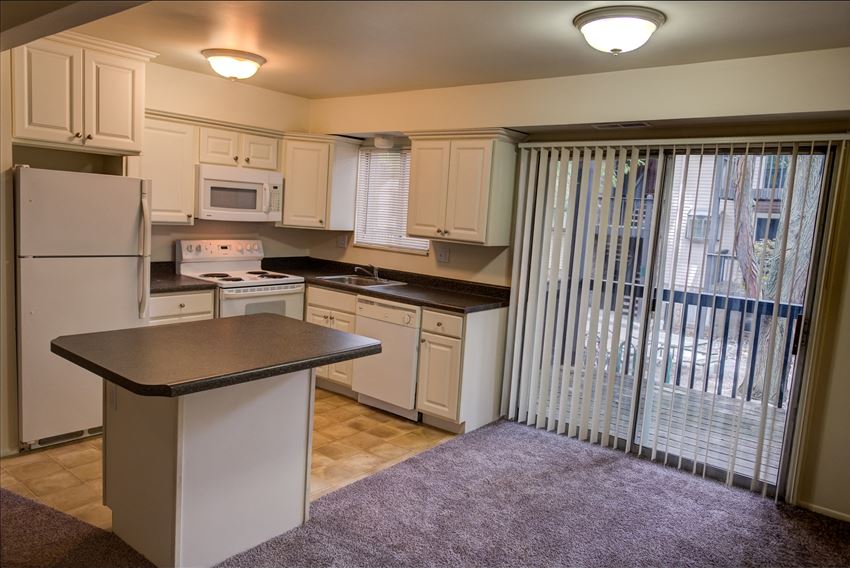 a kitchen with white appliances and a window with blinds
