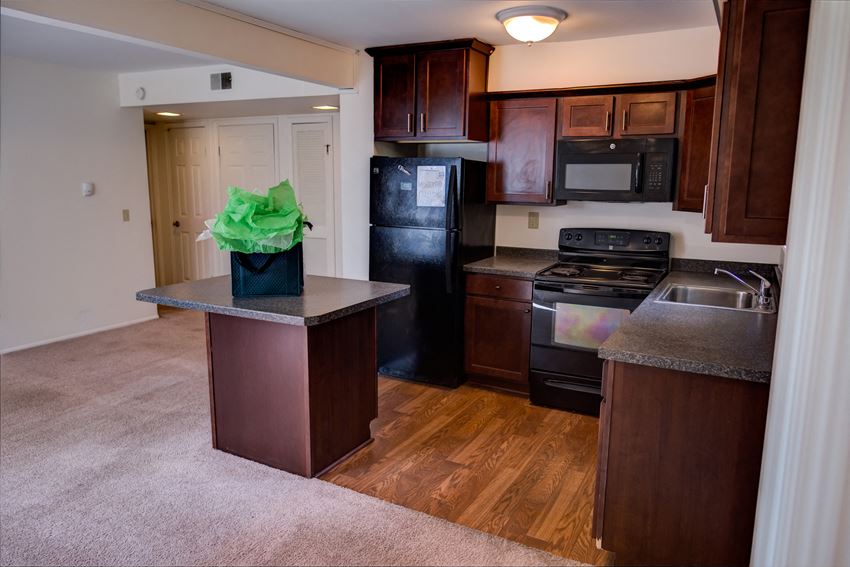 an empty kitchen with dark wood cabinets and stainless steel appliances