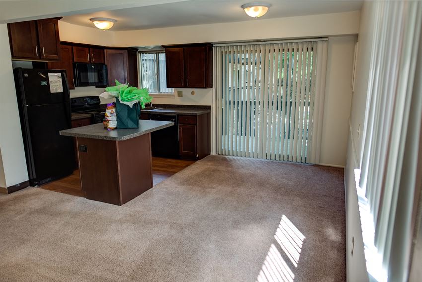 an empty living room and kitchen with blinds on the window