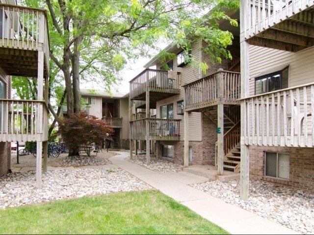 the courtyard of an apartment building with trees and a sidewalk