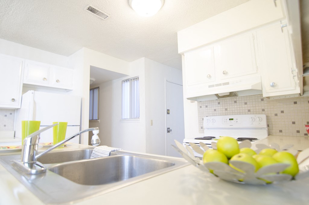 a white kitchen with a sink and a bowl of fruit