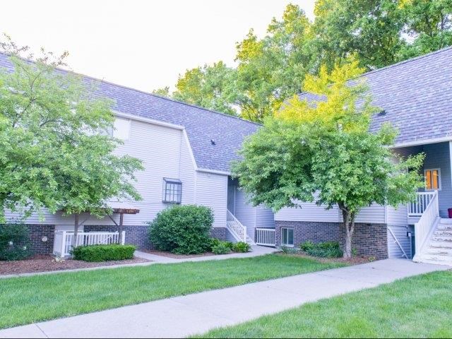 a white house with a sidewalk and trees in front of it