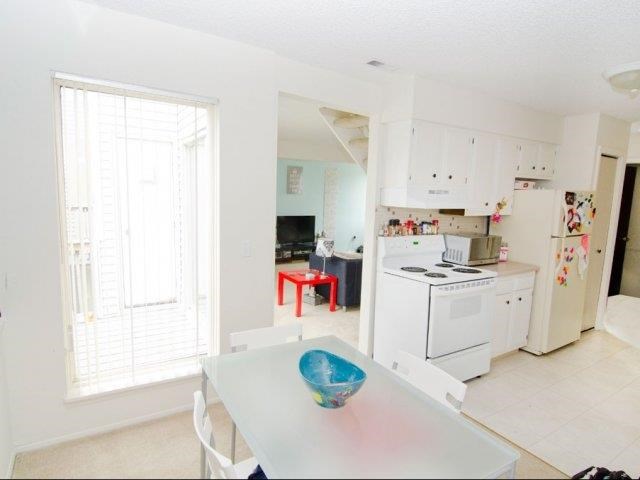 a white kitchen with a table and a refrigerator