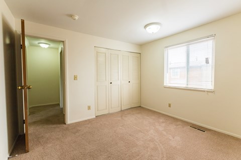 a bedroom with carpet and a door to a closet and a window