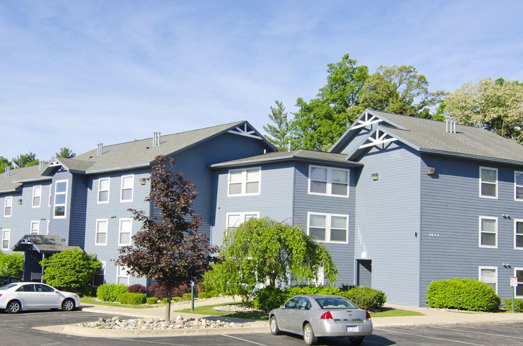 a blue apartment building with cars parked in front of it