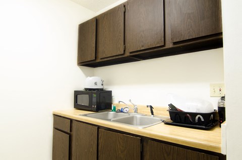 a kitchen with a sink and microwave in a hotel room