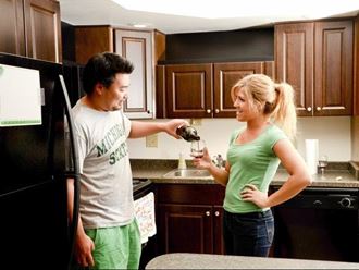 a man and a woman standing in a kitchen drinking wine
