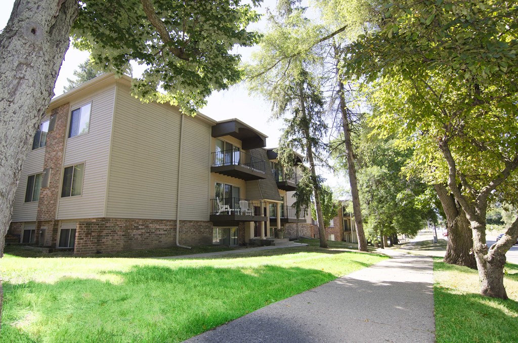an apartment building with a sidewalk and trees