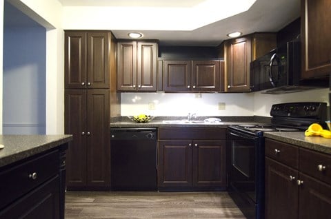 a kitchen with dark wood cabinets and black appliances