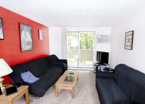 a living room with black couches and a red wall and a tv