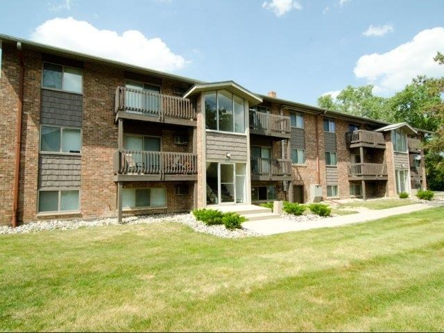 a brick apartment building with balconies and a grass yard