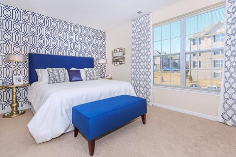 a bedroom with a large bed and a blue ottoman