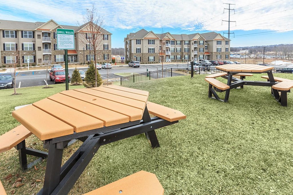 a group of picnic benches in front of an apartment building