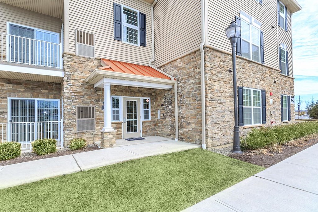 the front entrance of a building with a sidewalk and grass